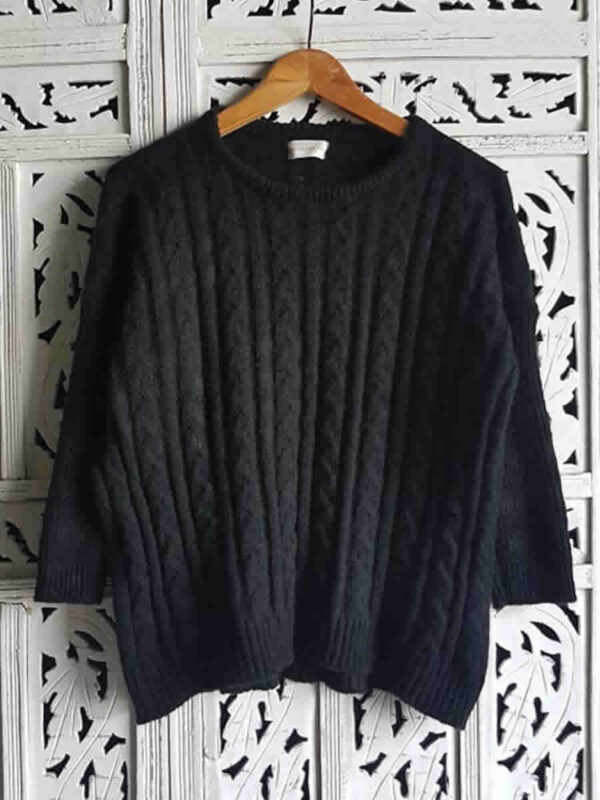 Sweater negro tejido con ochos, presentado en percha.