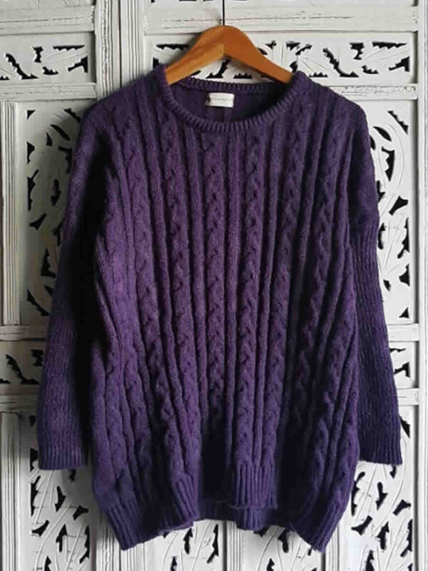 Sweater color uva tejido con ochos, presentado en percha.