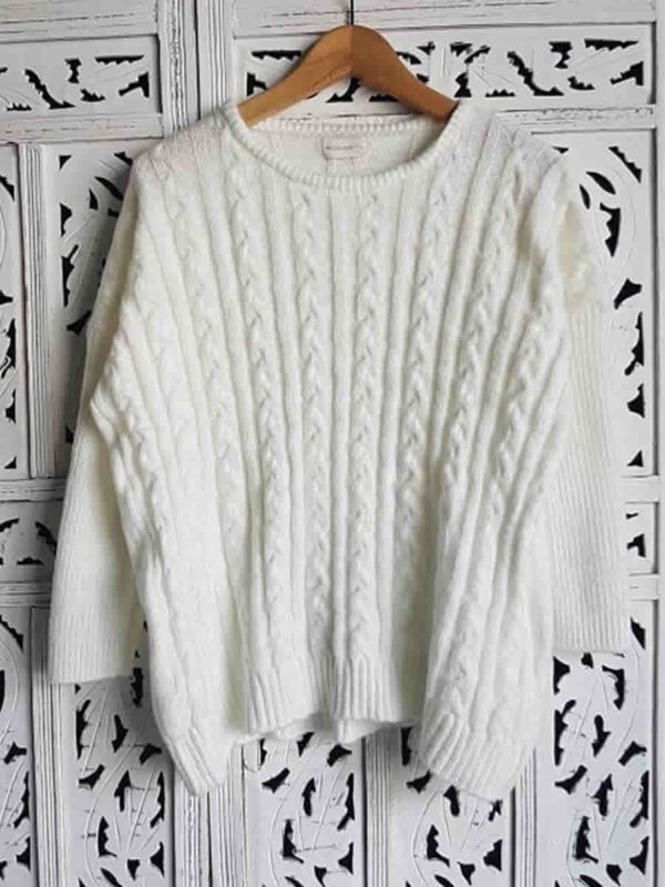 Sweater color crudo tejido con ochos, presentado en percha.
