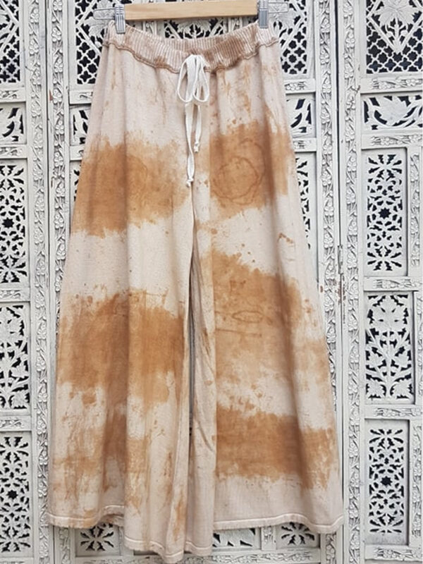 Pantalón tejido de color marrón con proceso de batiqueado sobre un fondo labrado crudo.