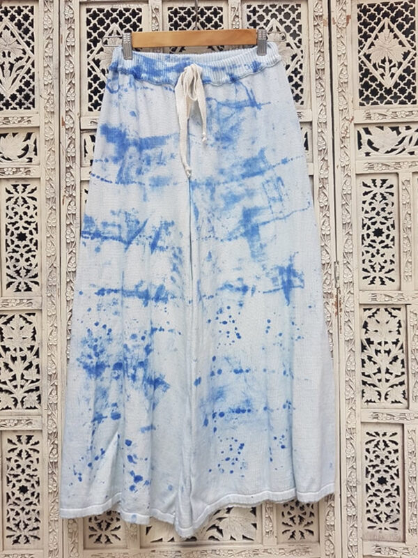Pantalón tejido de color azul con proceso de batiqueado sobre un fondo labrado crudo.
